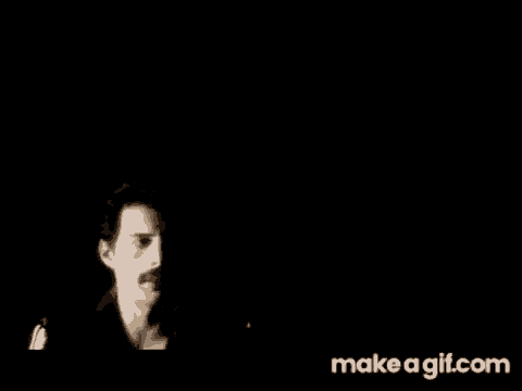 a man with a mustache is standing in the dark in a black background .