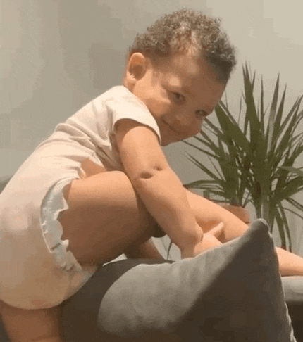 a baby is sitting on a pillow on a couch and smiling .