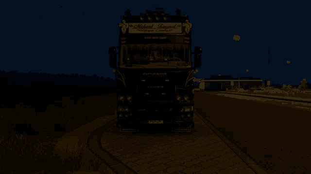 a scania truck is parked on the side of a road at night