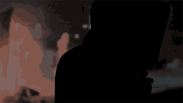 a man in a hoodie is standing in front of a fire .