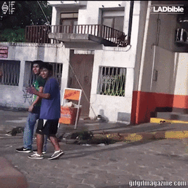 two men are walking down a sidewalk in front of a building with a sign that says ' ladbible '