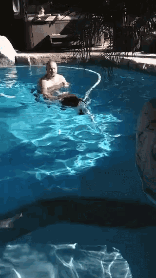 a man is swimming in a swimming pool with a hose attached to him