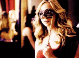 a woman wearing a mask is holding a necklace