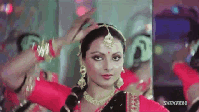 a woman in a red and black dress is dancing in front of a mirror with snehaboo written on the bottom