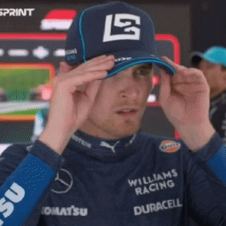 a man wearing a williams racing hat adjusts it