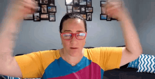 a woman wearing glasses is flexing her muscles while sitting on a couch .
