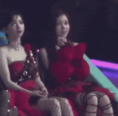 a couple of women in red dresses are sitting next to each other .