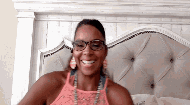 a woman wearing glasses and a pink tank top is smiling