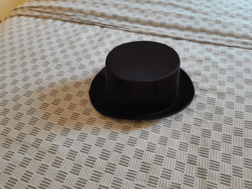 a black top hat is on a bed with a checkered pattern