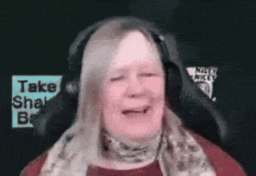 a woman wearing headphones and a scarf is sitting in a chair and smiling .