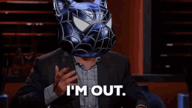a man in a suit with a spider-man mask on his head is saying i 'm out .