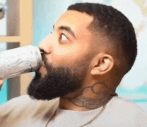 a man with a beard is drinking from a can of soda .
