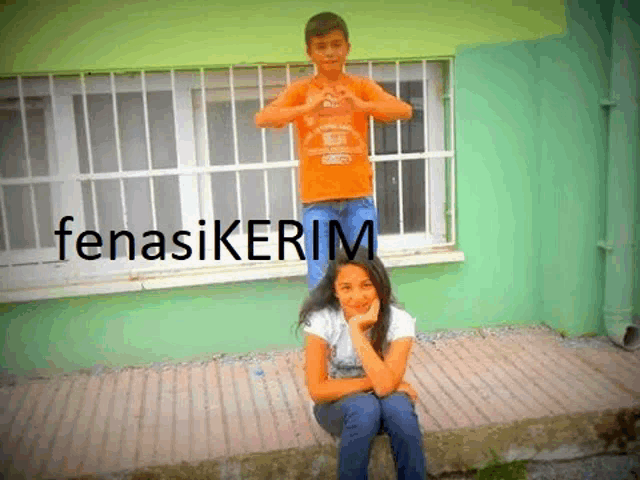 a girl sits on a boy 's shoulders in front of a green wall with fenasikerim written on it