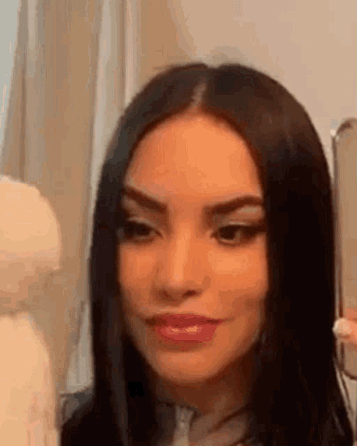 a woman is looking at herself in the mirror .