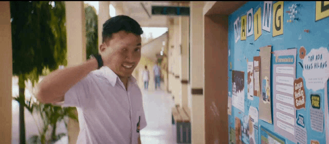 a man is standing in front of a bulletin board that says sading