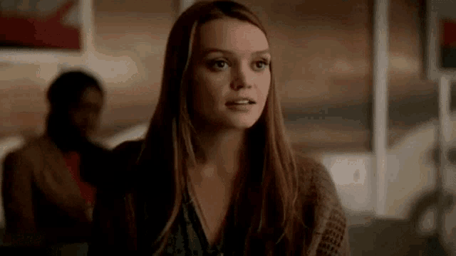 a woman with long hair is sitting at a table in a restaurant .