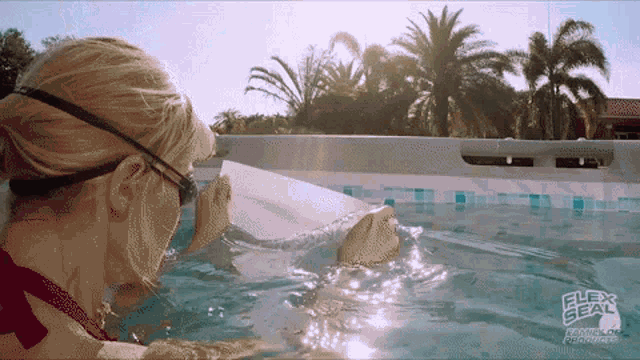 a woman is swimming in a pool that says flex seal on the side