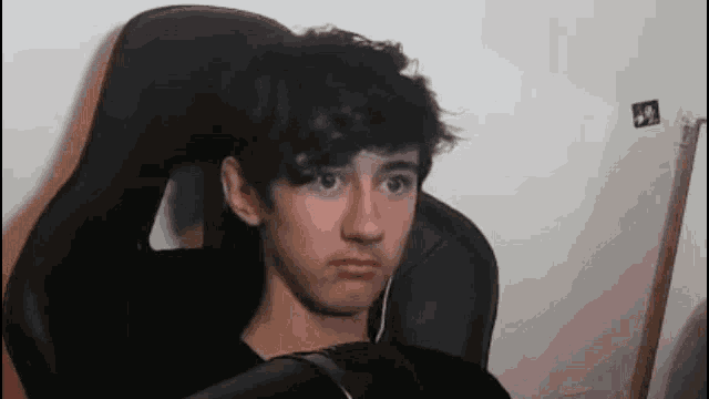 a young man is sitting in a black chair with headphones on his ears .