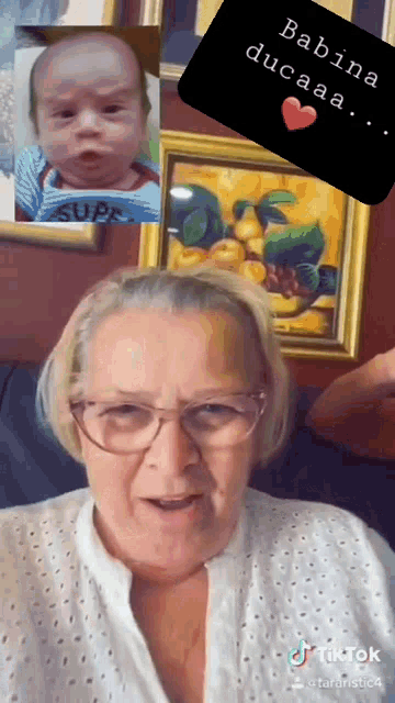 an elderly woman with glasses is talking to a baby in front of a painting
