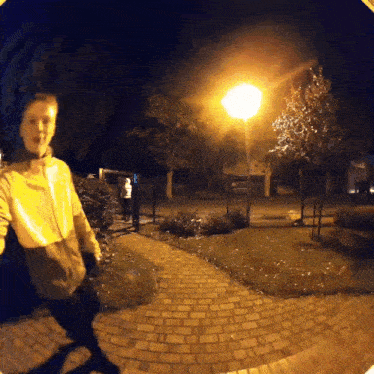 a person is walking down a brick path at night