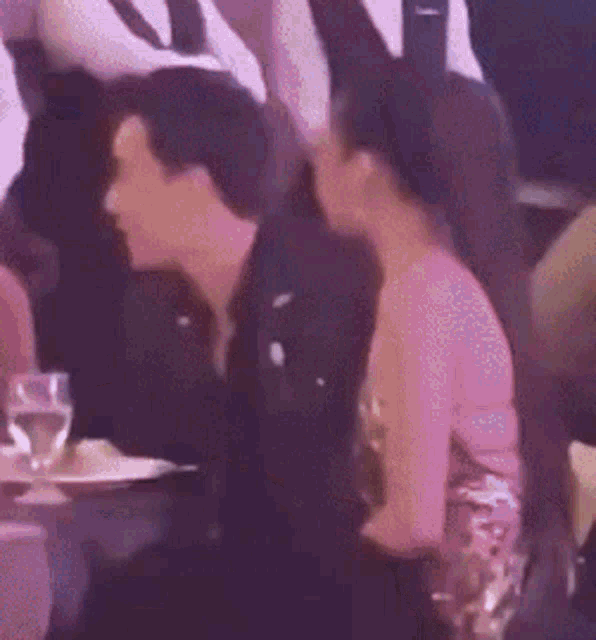a man and woman are sitting next to each other at a table with glasses of water .