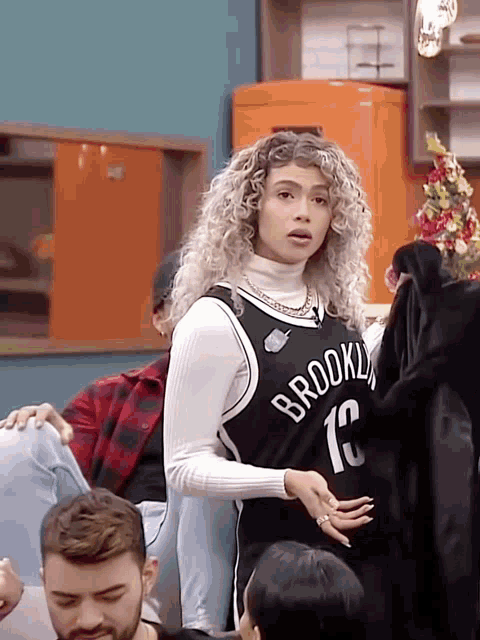 a woman in a brooklyn nets jersey stands in front of a group of people