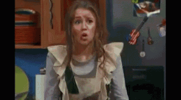 a woman in an apron is making a surprised face in a kitchen