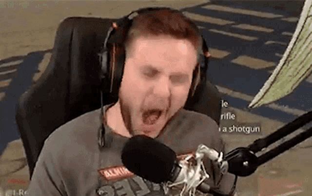 a man wearing headphones is sitting in front of a microphone and yawning .