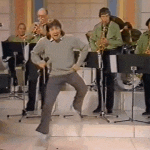 a man is dancing in front of a band with saxophones .