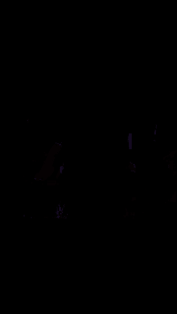 a man with a helmet on stands in a dark room with neon lights behind him