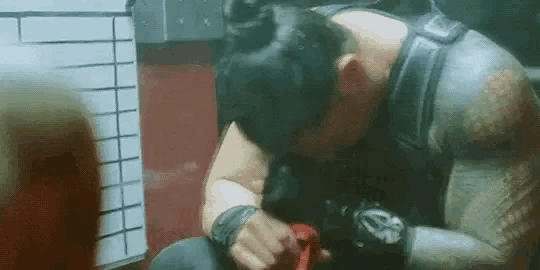 a man with a tattoo on his arm is sitting on the floor with his head down and looking down .