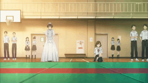 a group of people are standing in a gym and one of them is wearing a dress