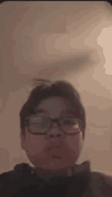a young man wearing glasses is taking a selfie in a room .