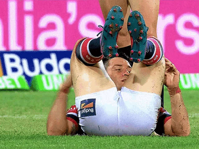 a soccer player is laying on his back with a budweiser sign behind him
