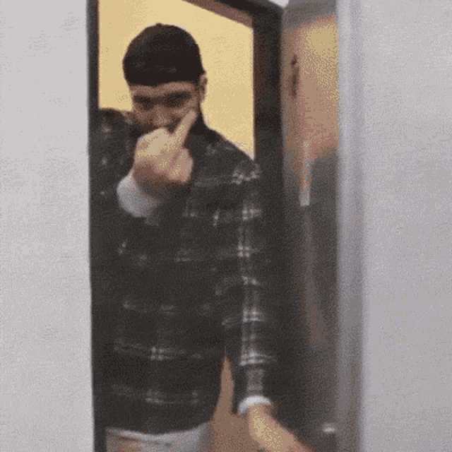 a man in a plaid shirt is giving the middle finger .