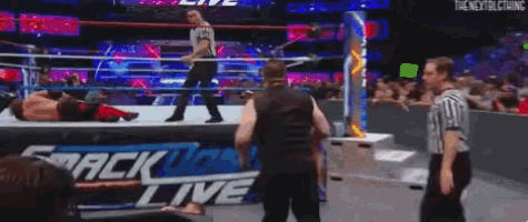a wrestling match is being held in a ring with a referee watching .