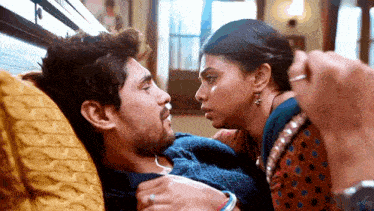 a man and a woman are laying on a couch and the woman is touching the man 's face