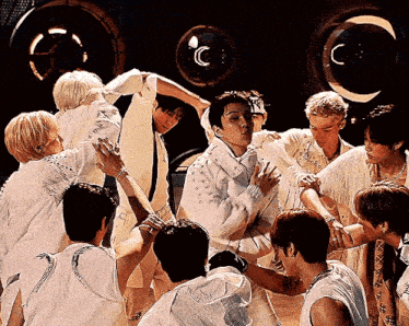 a group of young men are gathered around a man in a white shirt