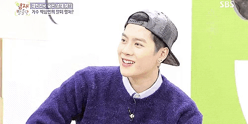 a young man wearing a purple sweater and a black baseball cap is smiling .