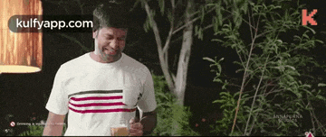 a man in a white shirt is holding a cup of coffee and laughing .