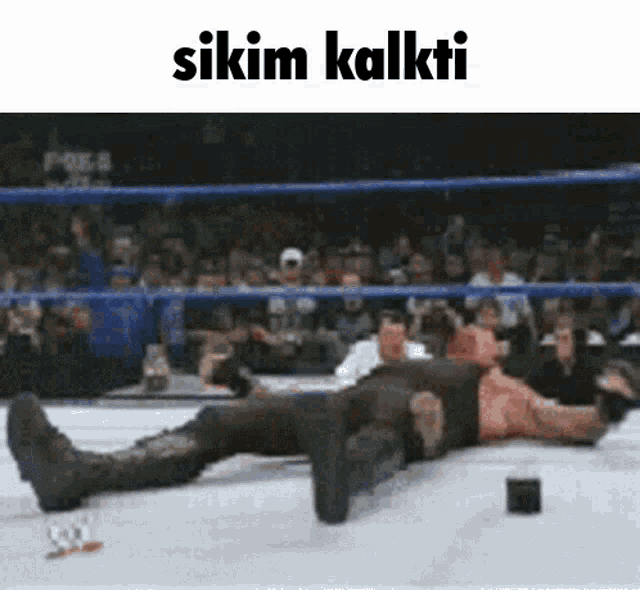 a man is laying on the ground in a wrestling ring with the words " sikim kalkti " on the bottom