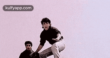 a couple of men are standing next to each other on a pink background .