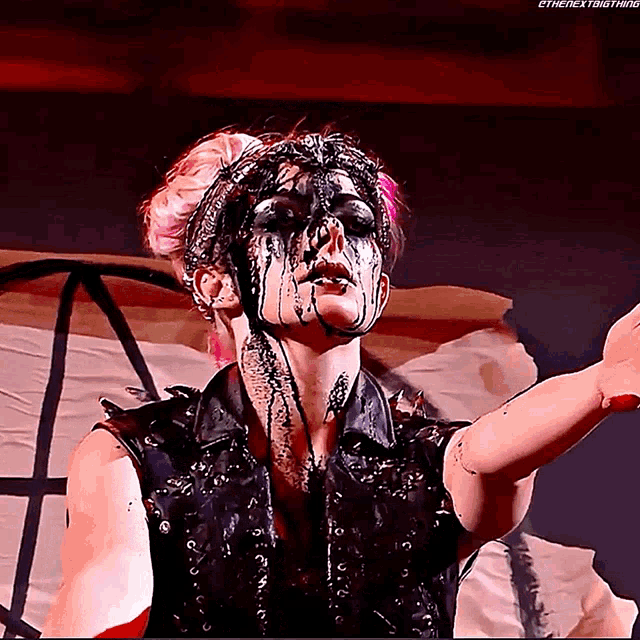a woman with black paint on her face is wearing a leather vest