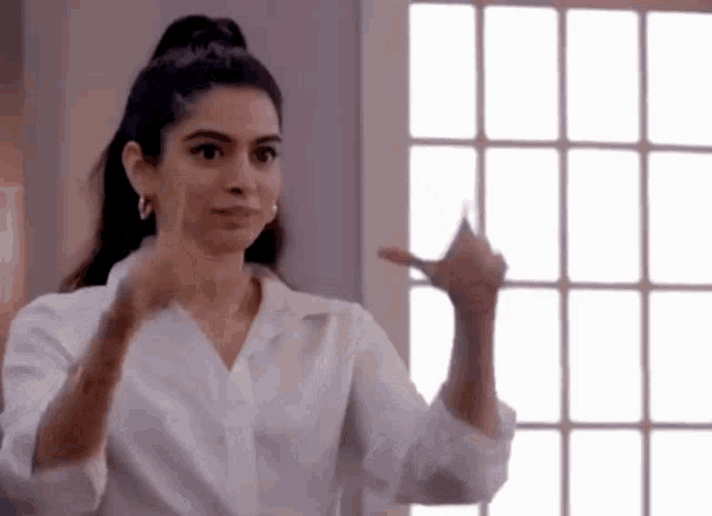 a woman in a white shirt is pointing at a window .
