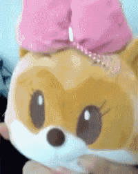 a stuffed animal with a pink bow on its head is being held by a person .