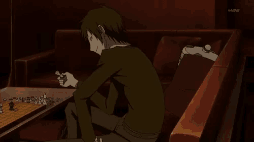 a man is sitting on a couch with a chess board in front of him ..