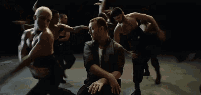 a man is sitting in front of a group of men dancing