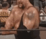 a man is standing in a wrestling ring with a barbell .