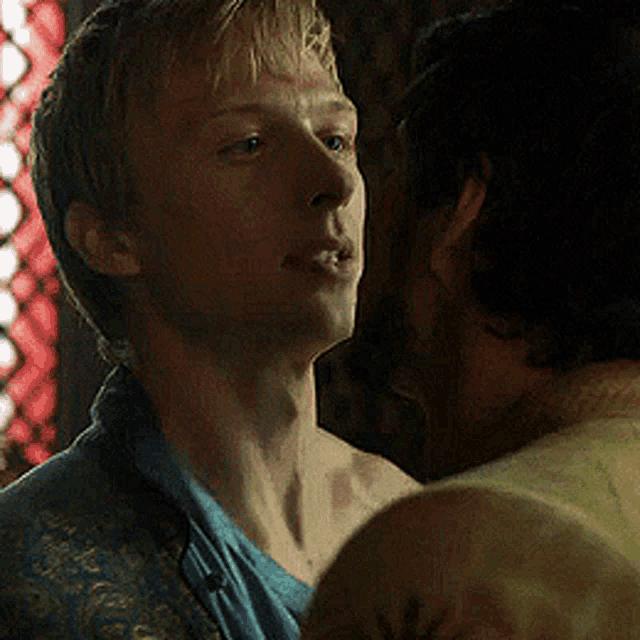 a man in a blue shirt is looking at another man in a yellow shirt