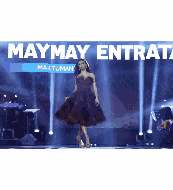 a woman in a red dress stands on a stage under a maymay entrata banner